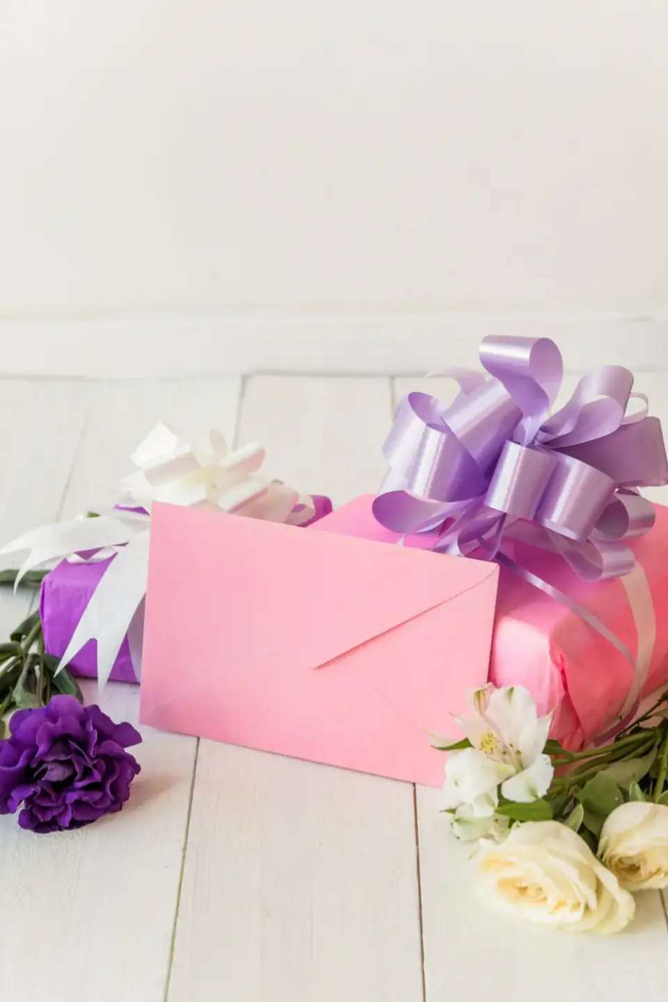 Geschenkbox mit lila Schleife und Blumen