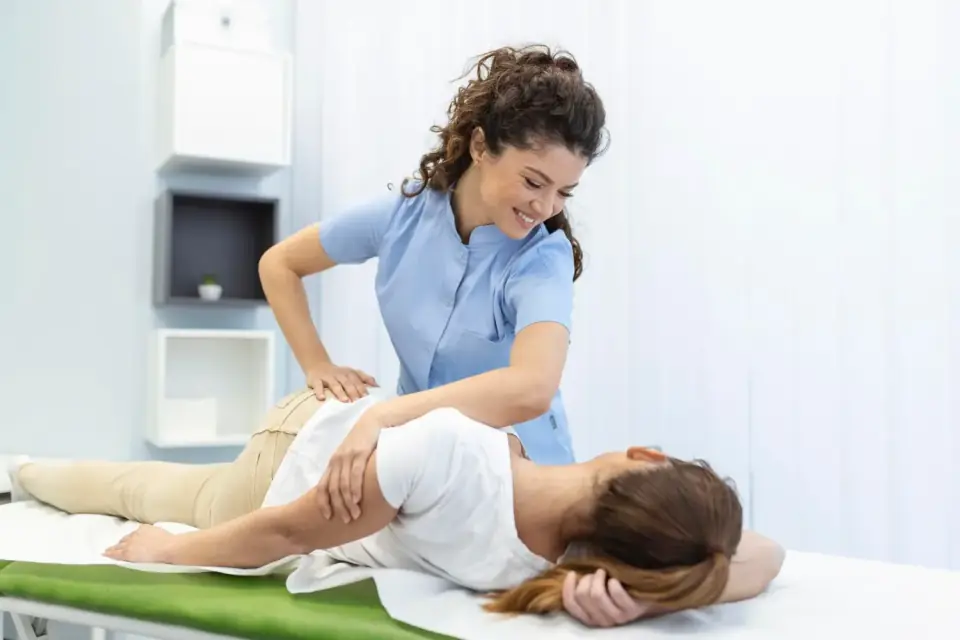 Therapeutin behandelt das Bein einer liegenden Patientin